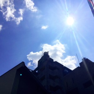 建物の隙間から太陽が見えている空